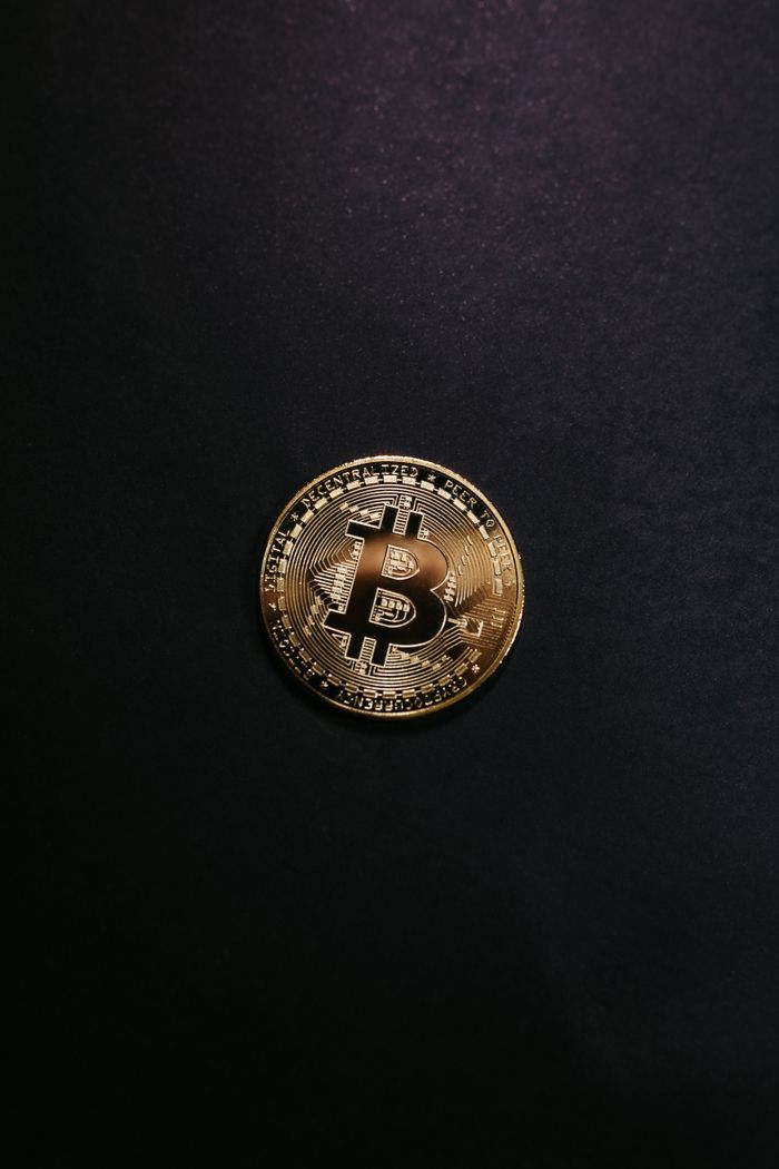 Close-up of a shiny gold bitcoin on a black background, symbolizing cryptocurrency.